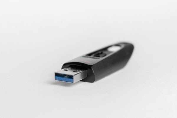 A black USB flash drive with a blue USB connector lies on a white surface. The drive's sleek design conveys a modern and minimalist feel.